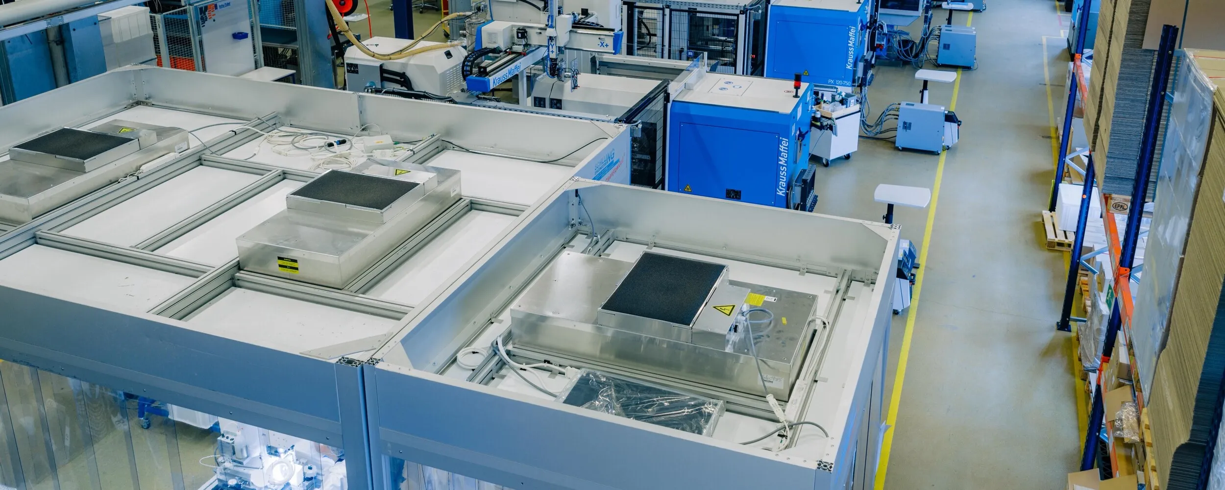 Large production hall equipped with several injection molding machines and automated systems for the manufacture of plastic components.